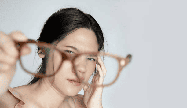 Asian beautiful woman is looking to her glasses with problem of her eye