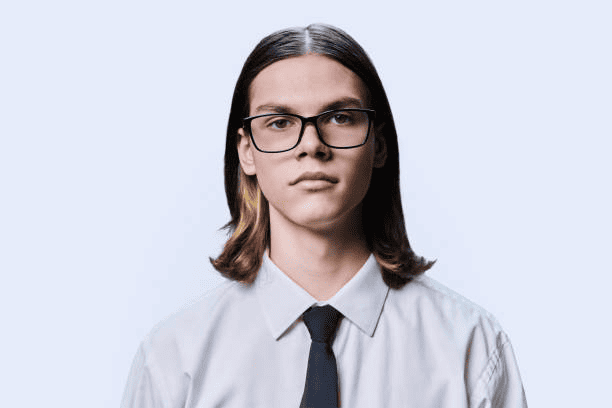 Headshot portrait of serious teenage guy on light studio background