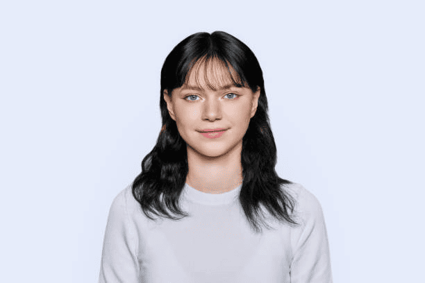 Smiling young female looking at camera on light background stock photo